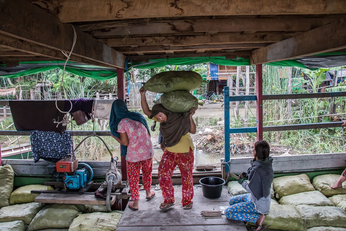 Locals load charcoal bags onto a boat near Katha, Myanmar. The boat is bound for Bhamo, where the charcoal will be taken by trucks over the border to China.