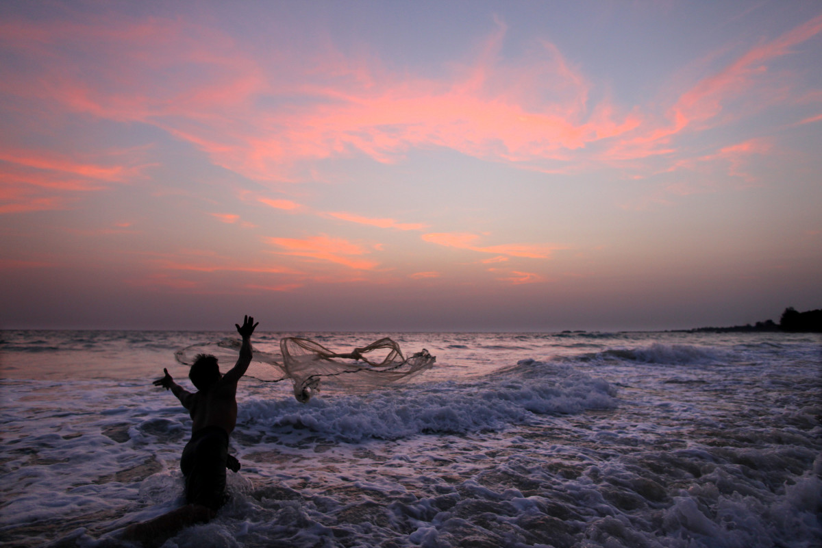 A fisherman throws a net out to catch small fish on the Nagapali Beach along the Bay of Bengal in Myanmar.