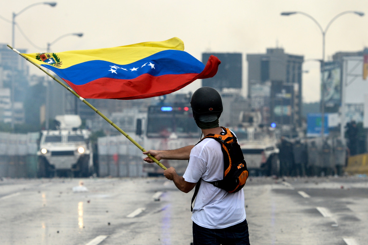 A Venezuelan opposition demonstrator waves a flag at the riot police in a clash during a protest against President Nicolas Maduro on May 8th, 2017.