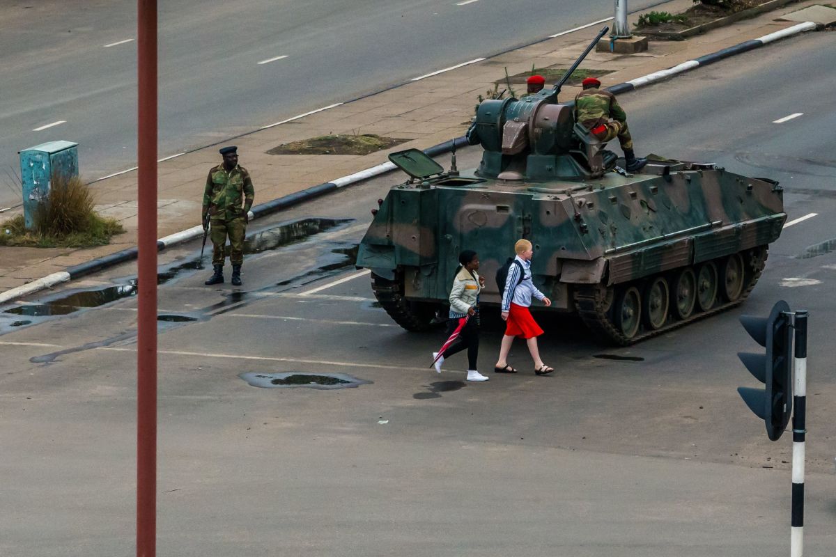 Pedestrians pass a tank stationed at an intersection as Zimbabwean soldiers regulate traffic in Harare on November 15th, 2017. Zimbabwe's military placed President Robert Mugabe under house arrest and took control of the country in an apparent coup on Wednesday.