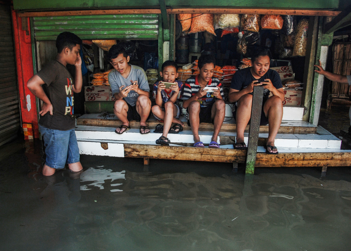 Indonesian youths play at a game center surrounded by floodwaters after seasonal rains hit Bandung on November 17th, 2017.