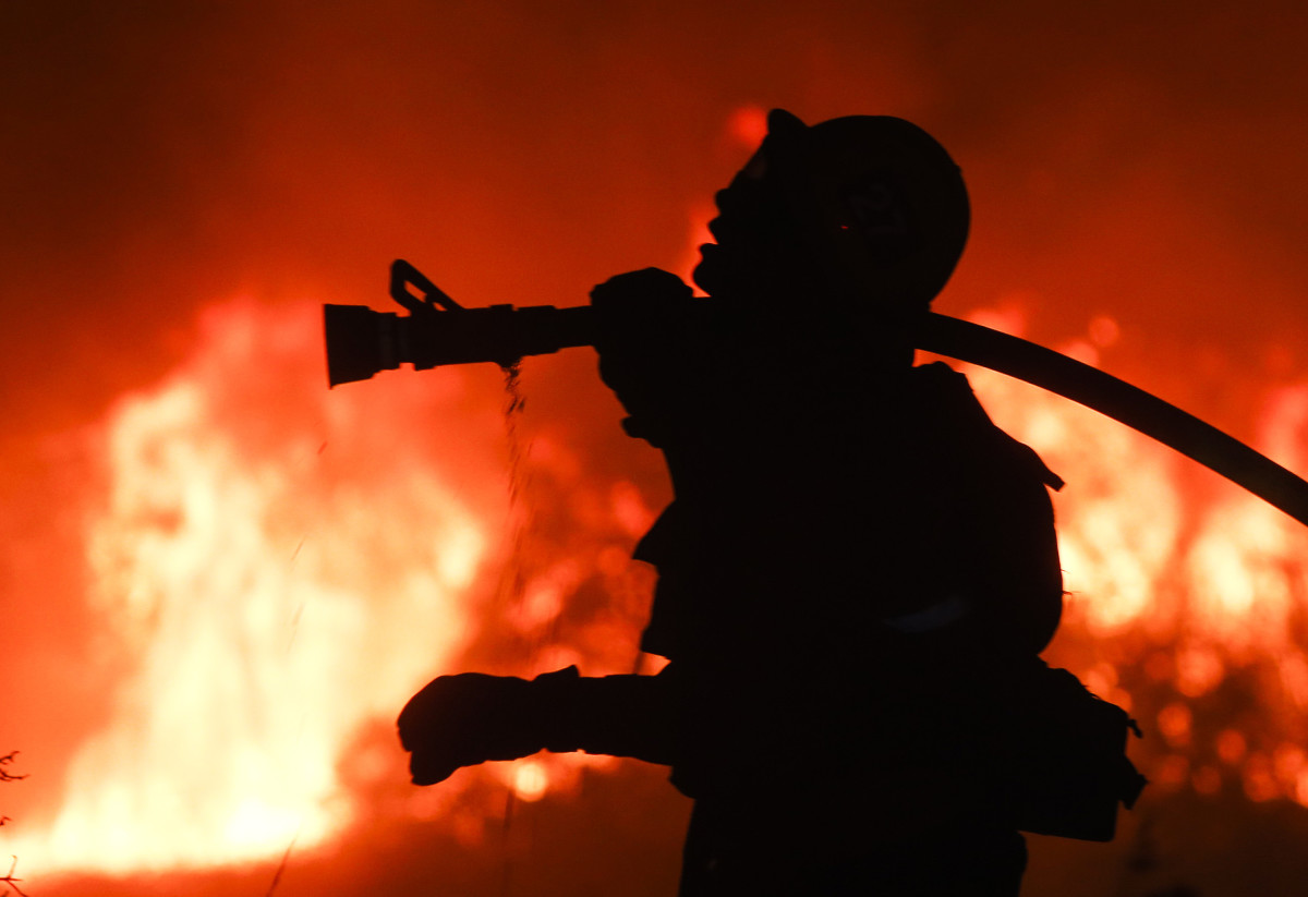 A firefighter battles a wildfire as it burns along a hillside near homes in Santa Paula, California.
