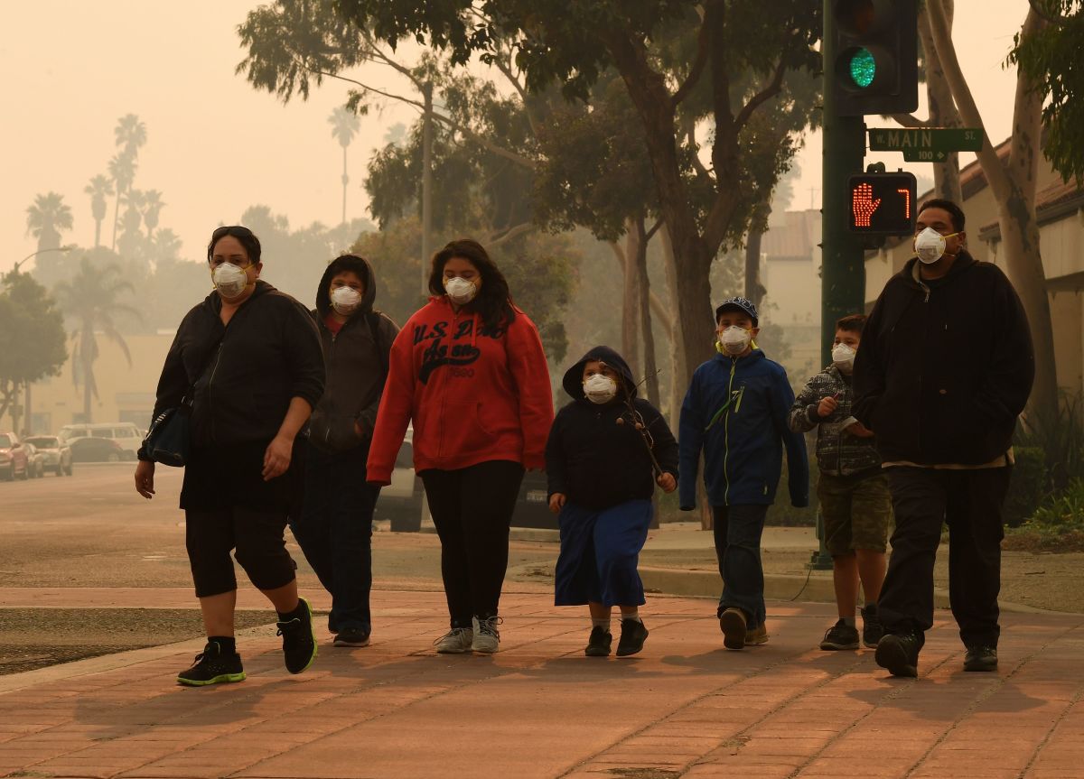 A family wears face masks as they walk through the smoke-filled streets of Ventura, California, on December 6th, 2017.