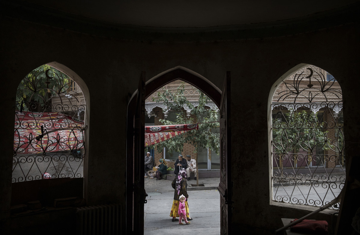 An ethnic Uyghur woman walks by a closed Islamic school on July 1st, 2017, in the old town of Kashgar, in the far western Xinjiang province, China.