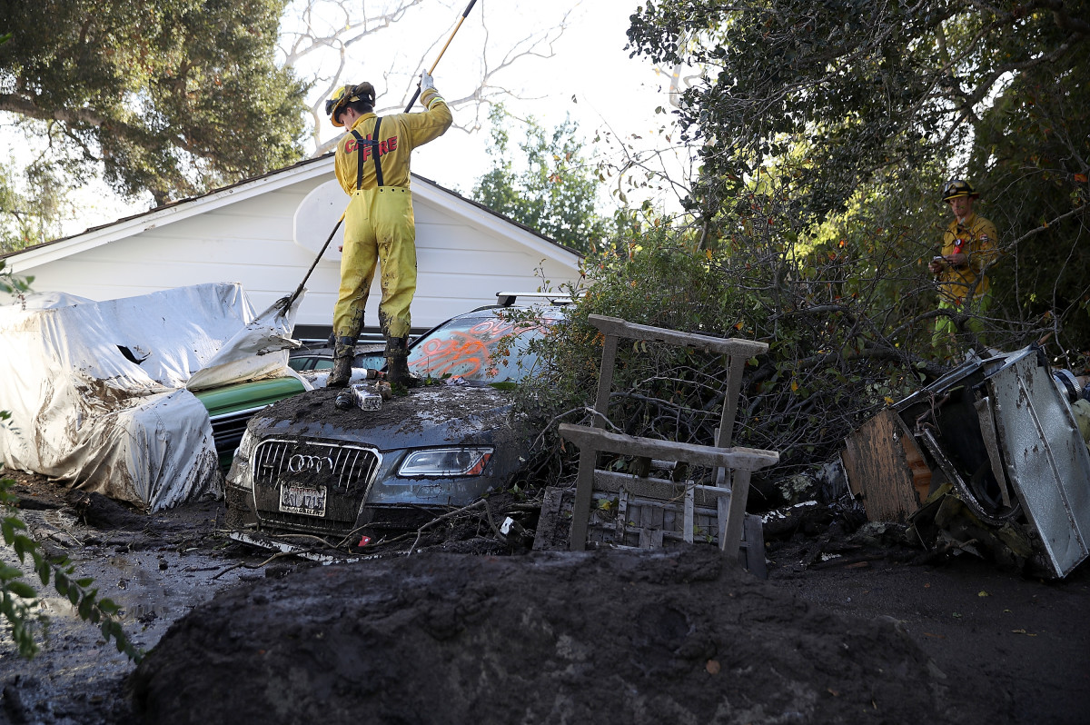 A Cal Fire firefighter looks through a car next to a home that was destroyed by a mudslide on January 12th, 2018, in Montecito, California.