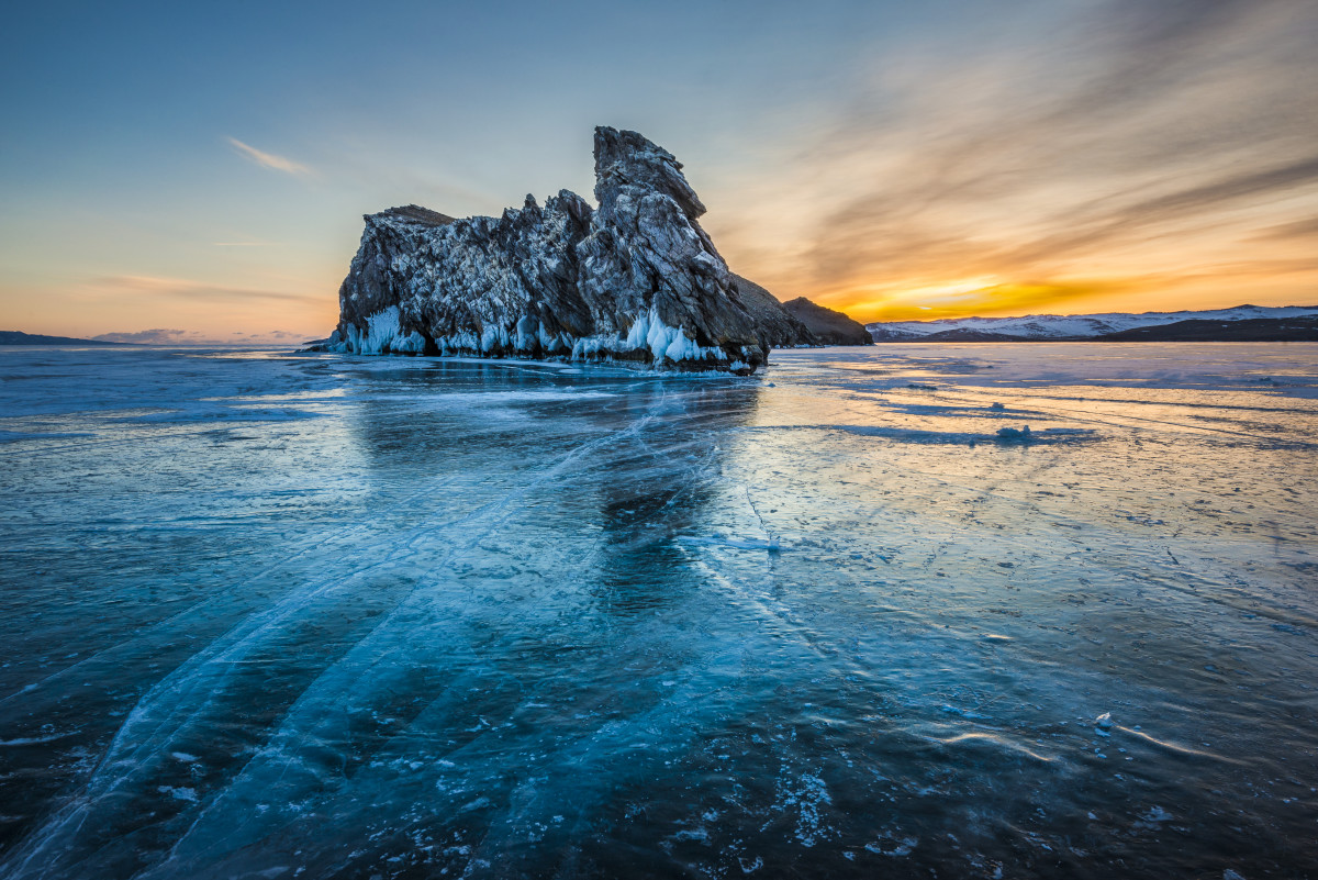 Siberia, Russia: A winter sunset near Ogoy Island on frozen Lake Baikal. With few passable roads, locals drive cars, jeeps, and even cargo lorries over the ice to shorten their journeys.