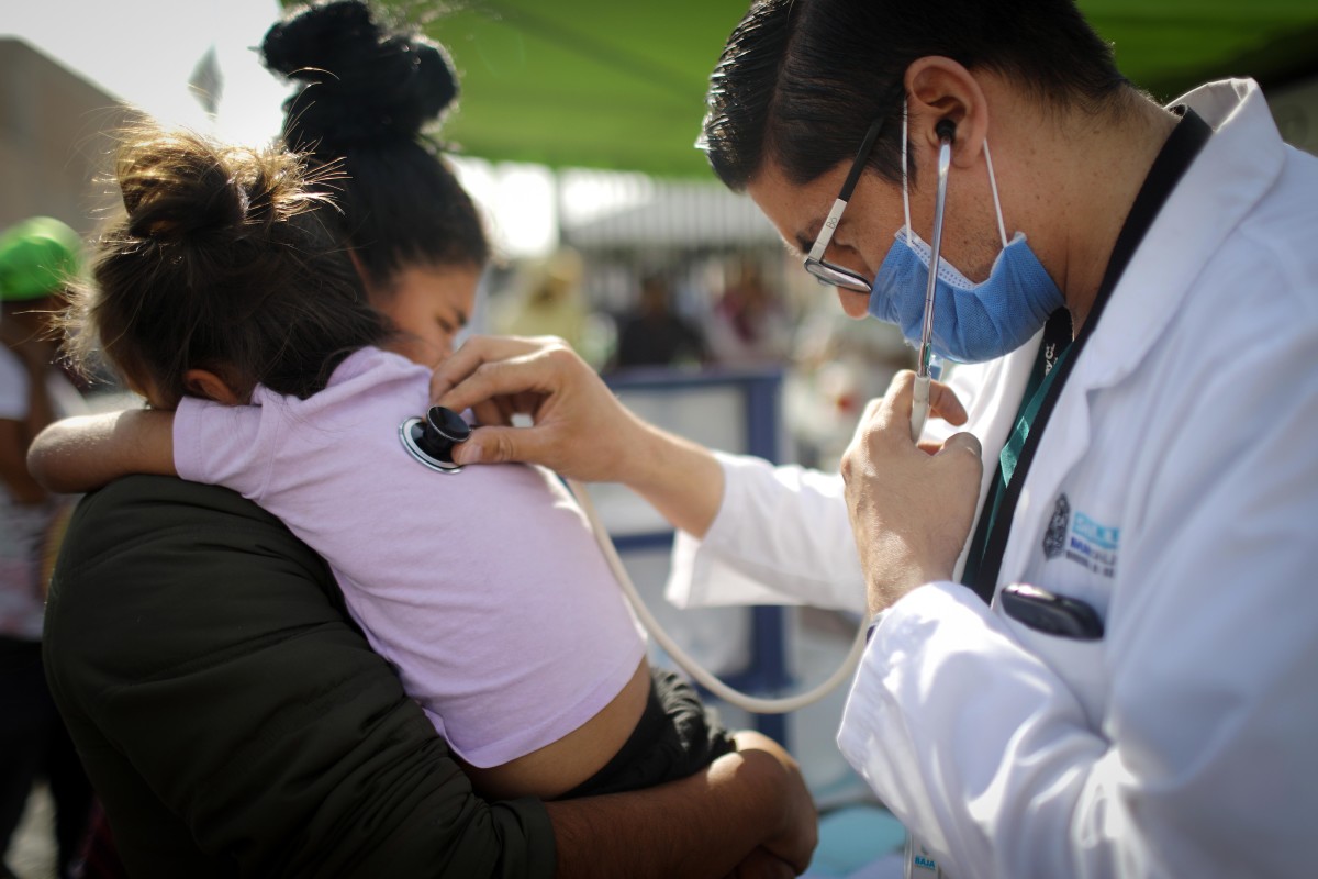 A Honduran mother holds her daughter, who fell ill, while being examined by a doctor outside a shelter for migrants on November 21st, 2018, in Mexicali, Mexico.