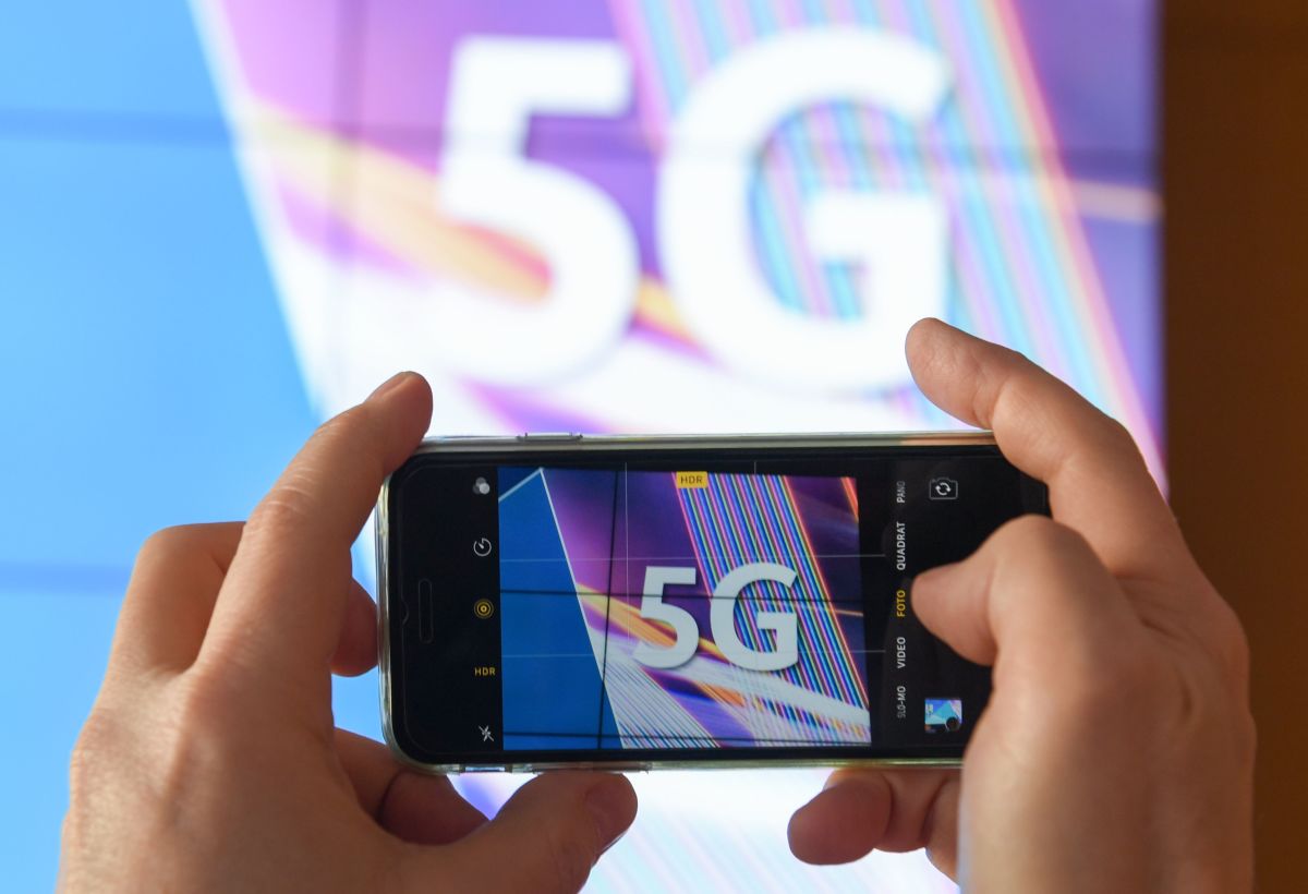 A journalist takes pictures of a projection screen prior to the start of Germany's auction for the construction of an ultra-fast 5G mobile network.