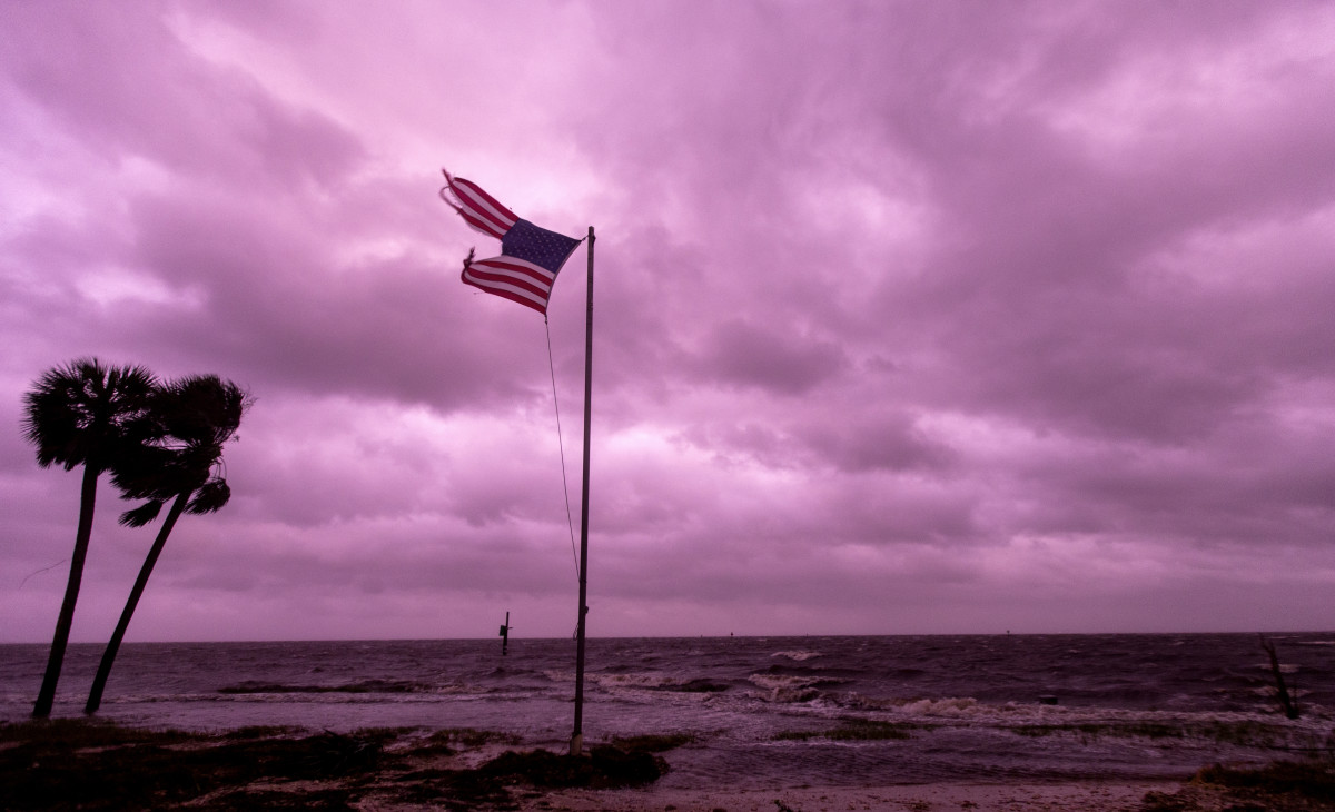 An American flag battered by Hurricane Michael waves against a rose-colored light of sunset at Shell Point Beach on October 10th, 2018, in Crawfordville, Florida.
