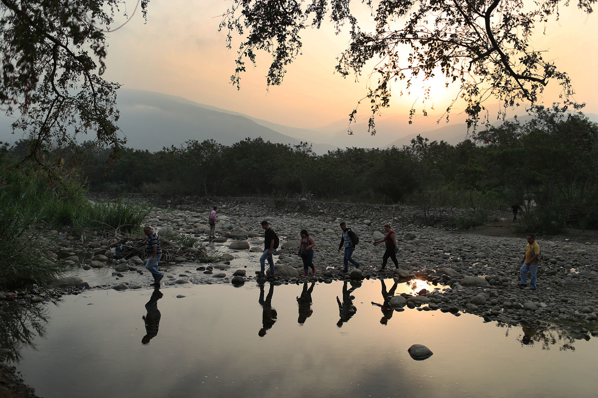 People cross the low waters of the Táchira River near the Simón Bolívar international bridge between Venezuela and Colombia on March 4th, 2019.