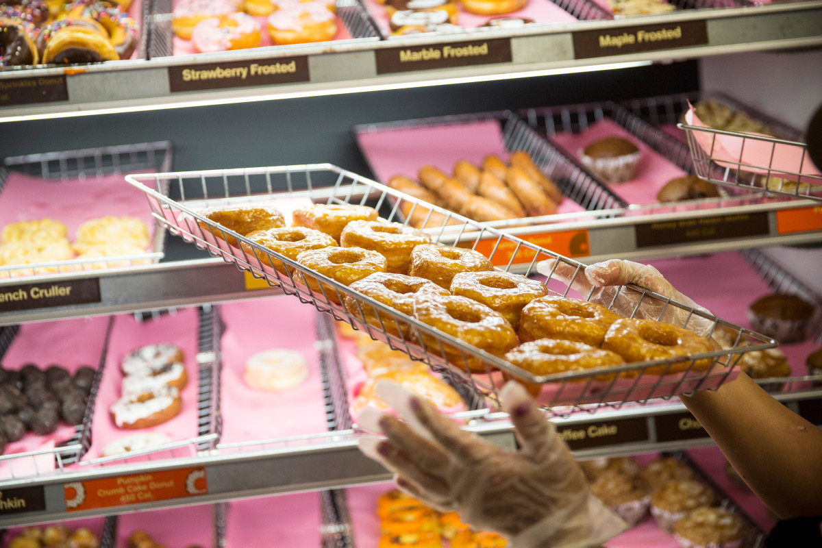 A Dunkin' employee places a fresh tray of doughnuts on the shelf in New York City.