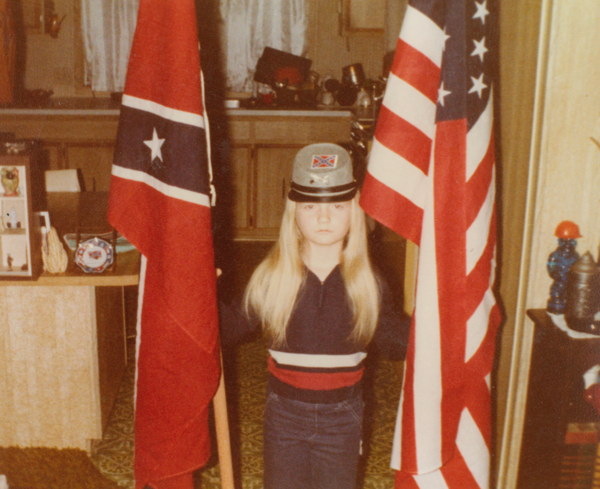 A young Jvonne Hubbard poses with American and Confederate flags.