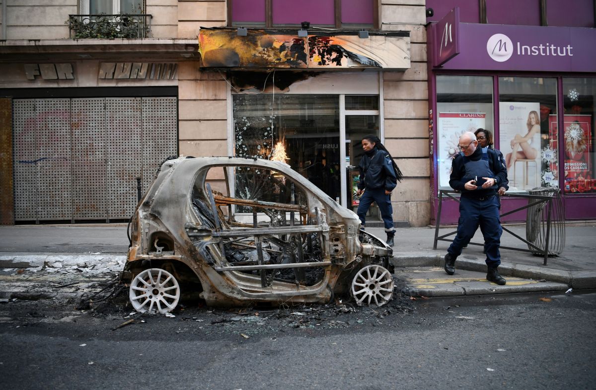 Police look at a burnt car in Paris, France, on December 9th, 2018—one day after "yellow vest" protests rocked the country. More than 1,700 people were arrested across France during the latest "yellow vest" protests against rising living costs.