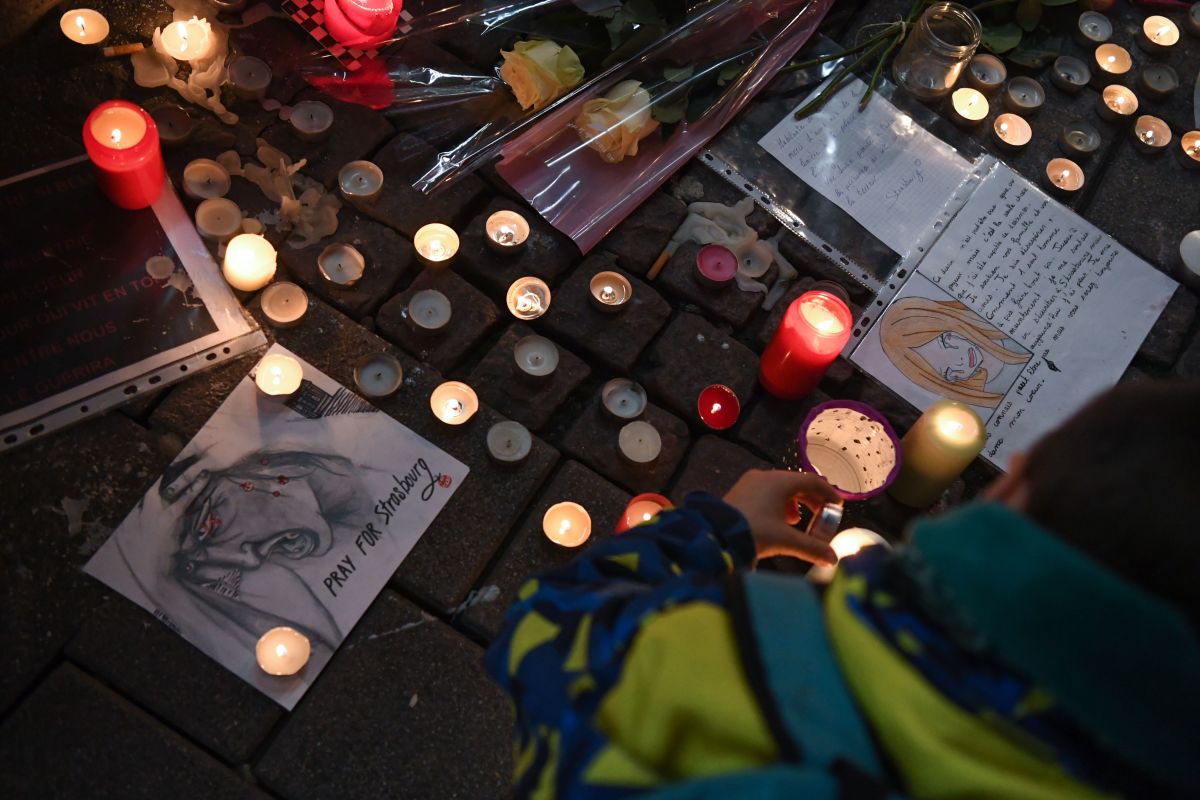 A man lights candles at a vigil on December 13th, 2018, in memory of the victims of an attack near the Christmas market of Strasbourg in France. Officials say three people were killed and 13 wounded when a lone gunman, identified as Cherif Chekatt, 29, opened fire on shoppers on December 11th.