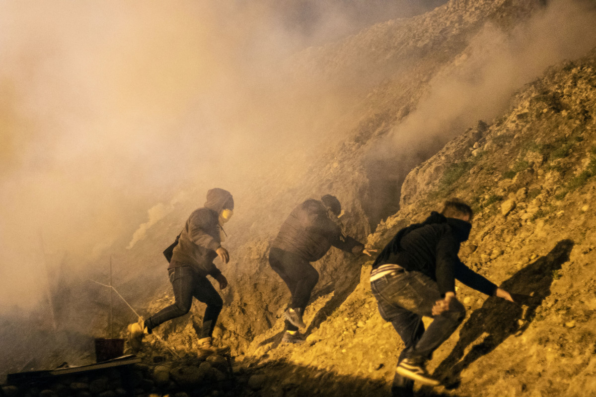 Central American migrants run away from tear gas thrown by the US border patrol, after they tried to cross from Tijuana to San Diego in the US, as seen from Tijuana, Baja California state, Mexico on January 1, 2019. - Around 100 Central American migrants made a failed attempt on New Year's Eve to cross over from Mexico into the United States. As night fell and people on both sides of the frontier prepared to celebrate New Year's Eve, the migrants tried to cross over but at least two smoke bombs were hurled and they ultimately held back.