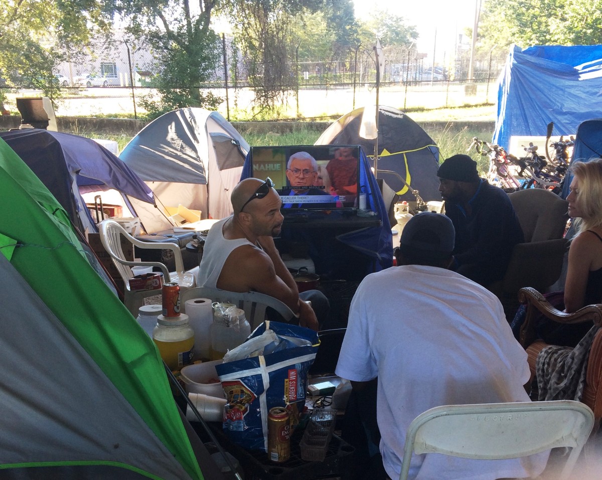 A group gathering at the Wheeler camp, one of the homeless encampments with generators that can power TVs.