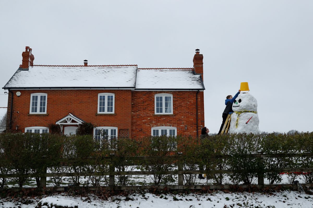 A boy puts a bucket for a hat onto the top of a snowman near Hartley Wintney, in Hampshire, 40 miles west of London, on February 1st, 2019. Snowfall and icy conditions were expected Friday to cause travel disruption after temperatures overnight reached as low as -15.4 degrees Celsius. An amber snow warning was issued for an area west of London including parts of Oxfordshire, Hampshire, and Buckinghamshire, after as much as 14 centimeters of snow fell on southwest England.