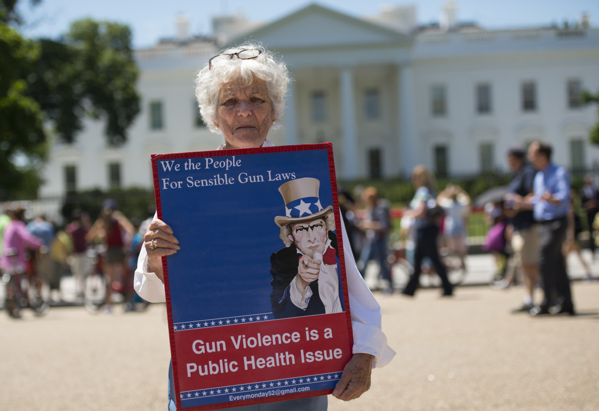 A woman walks with a sign to protest gun violence and call for sensible gun laws outside the White House in June of 2016. One advocacy group, Cure Violence, approaches violence as a public-health issue, and has seen success reducing gun violence.
