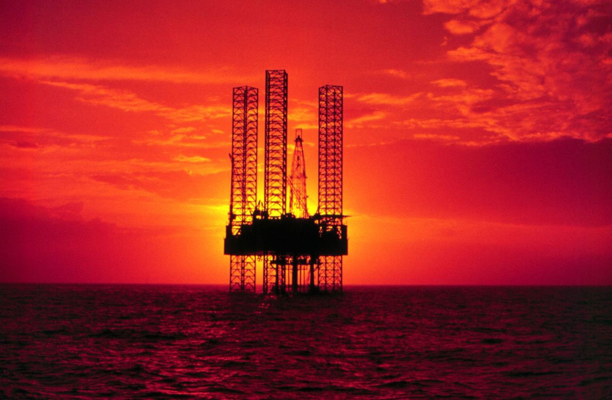 An offshore oil rig is pictured at sunset.