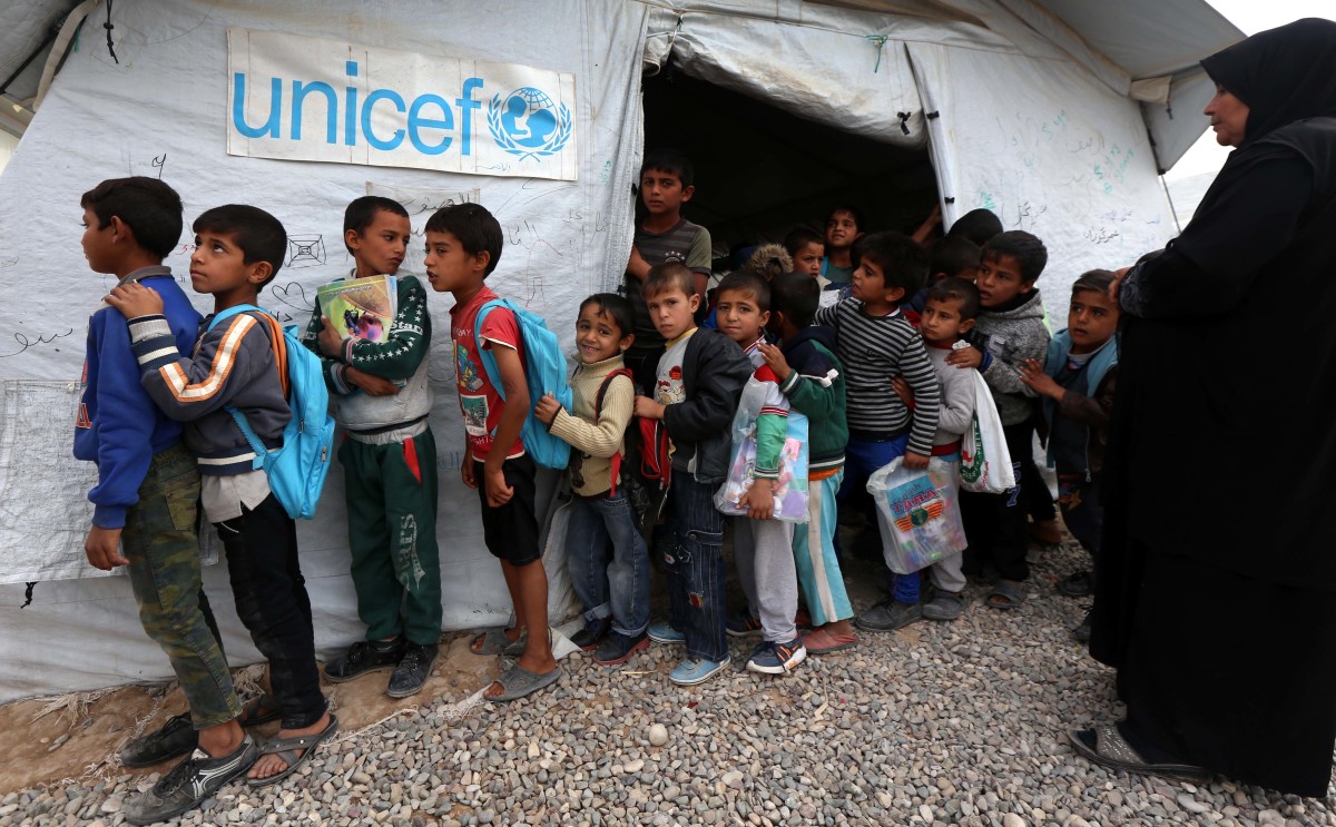 Displaced Iraqi children from the former embattled city of Mosul line up outside a UNICEF school.