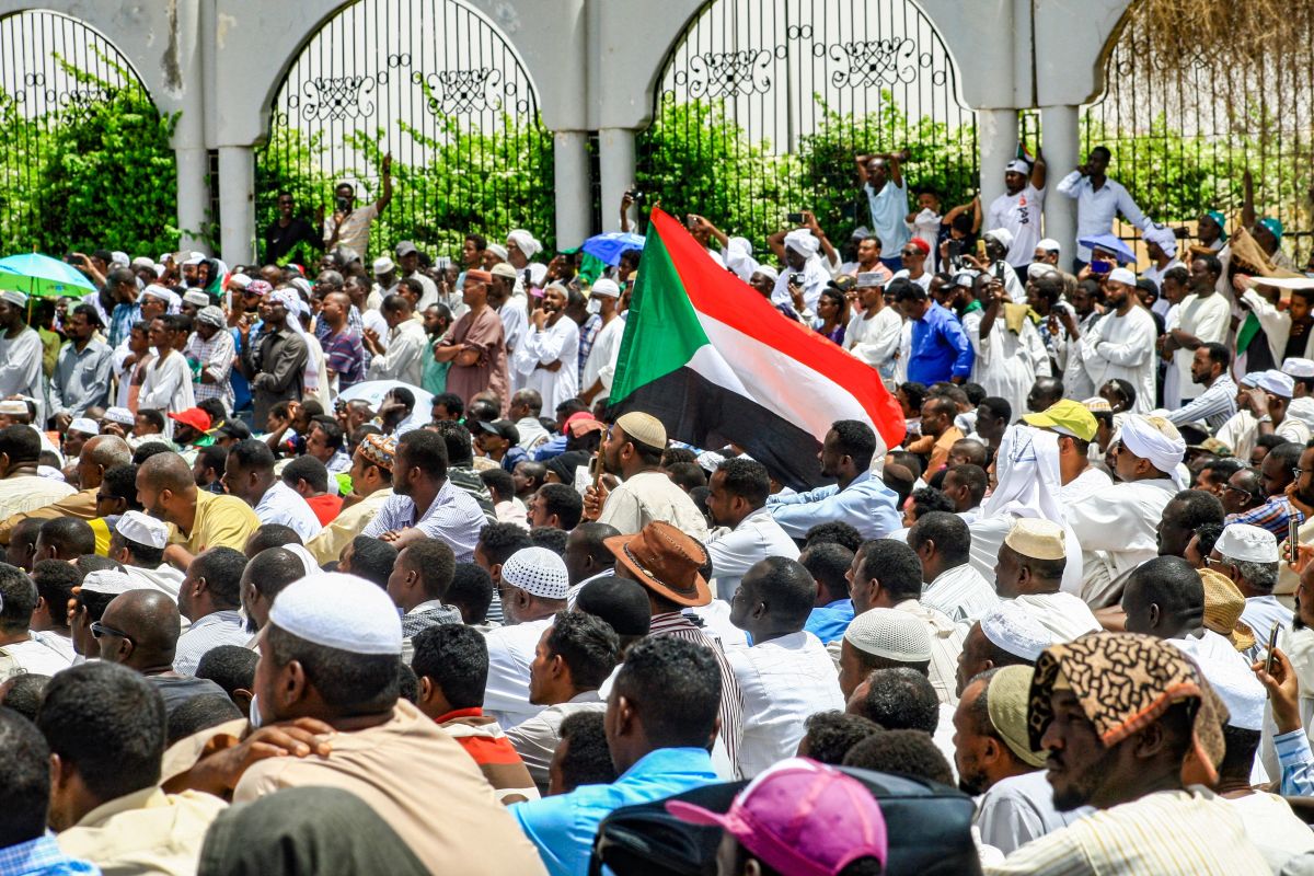 Sudanese men sit as they attend a Friday prayers sermon during a rally on April 12th, 2019.