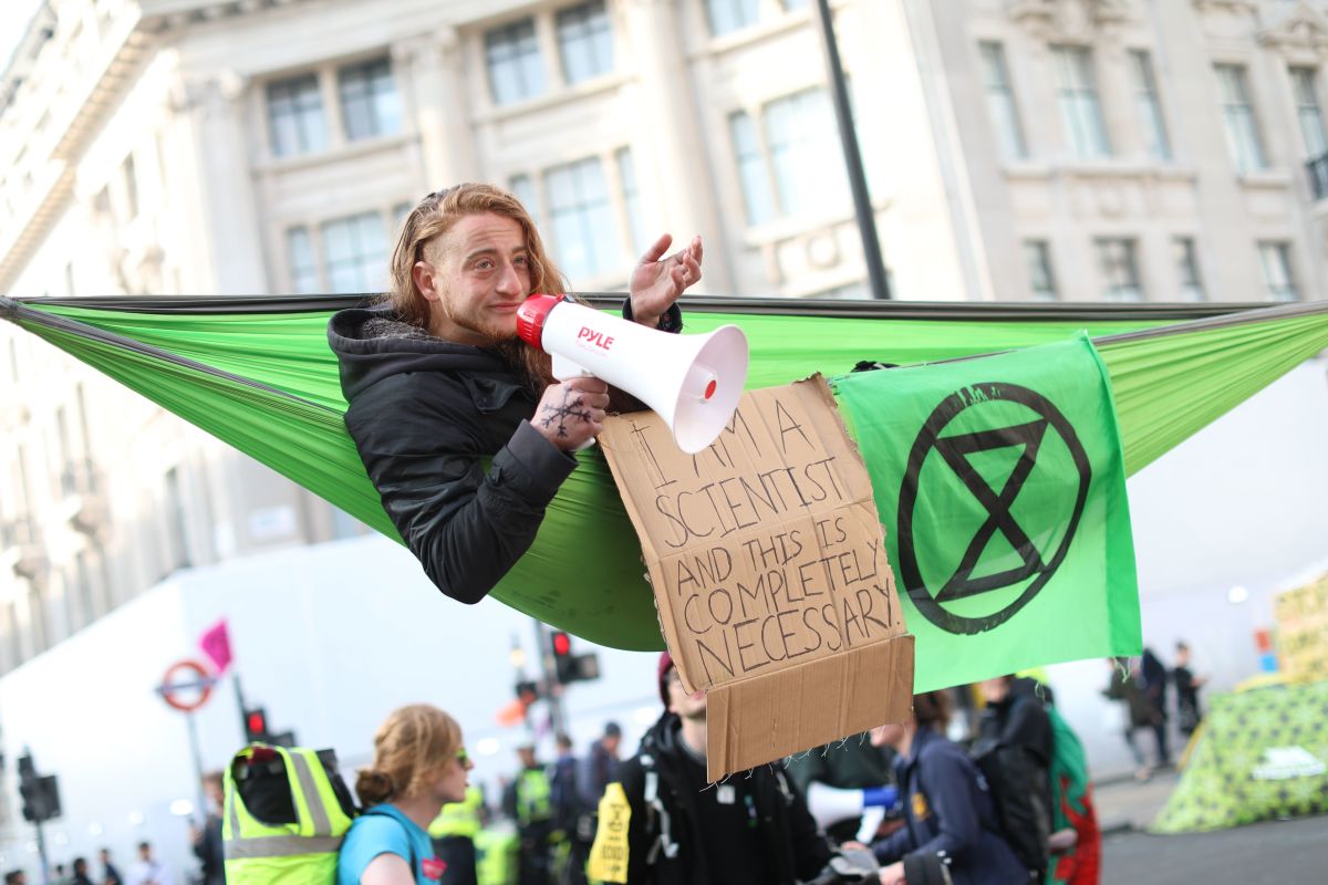 A climate change activist in a hammock occupying Oxford Circus in the busy shopping district of central London on April 18th, 2019, uses a megaphone on the fourth day of an environmental protest by the Extinction Rebellion group.
