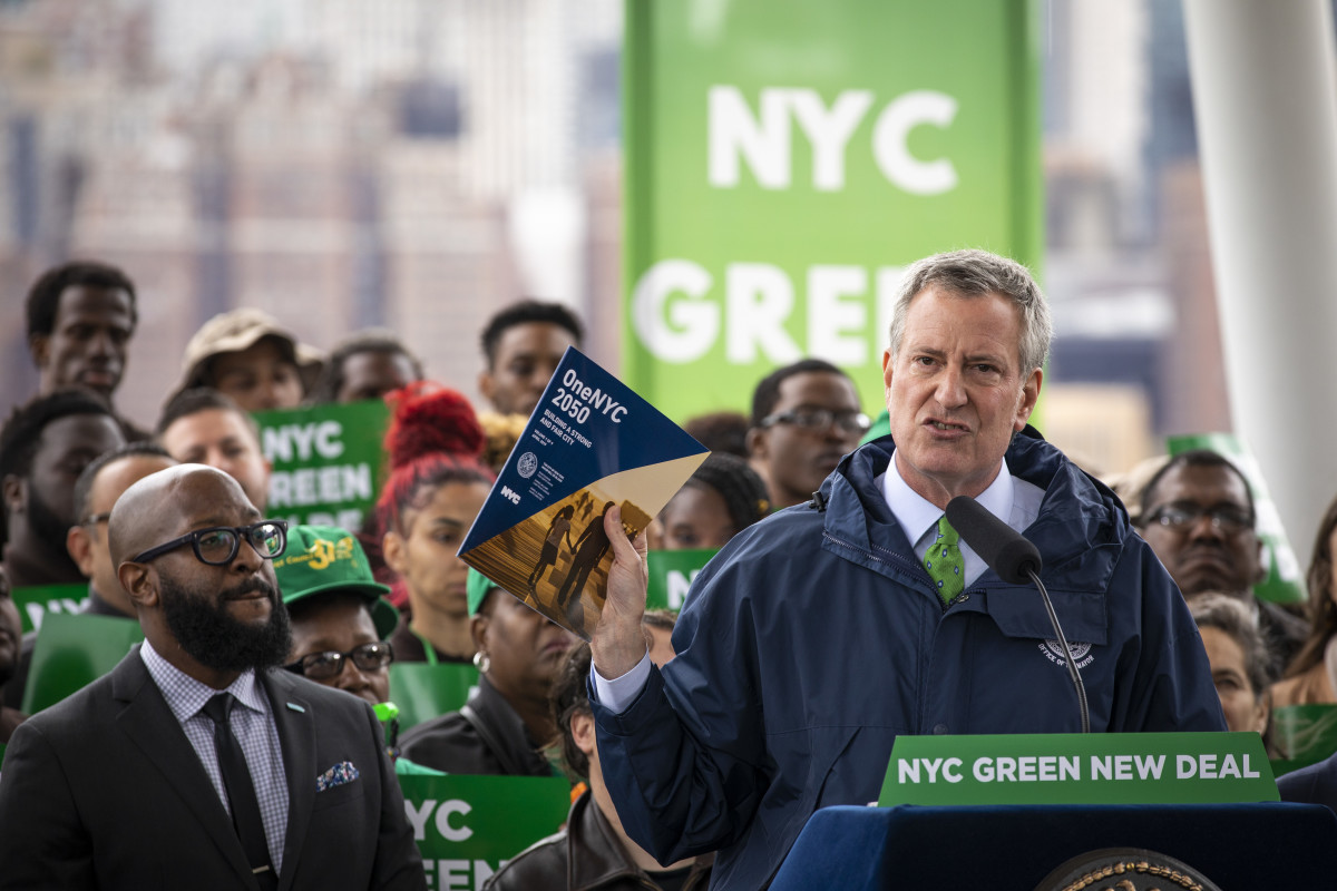 New York City Mayor Bill de Blasio holds up a copy of One NYC 2050 as he speaks the city's response to climate change at Hunters Point South Park on April 22nd, 2019.