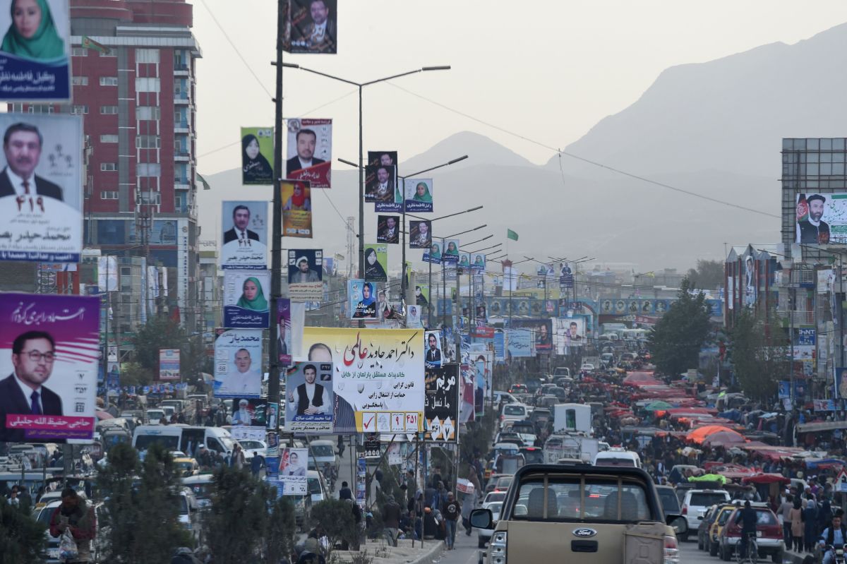 Kabul commuters drive along a road with posters of candidates hanging from street posts.