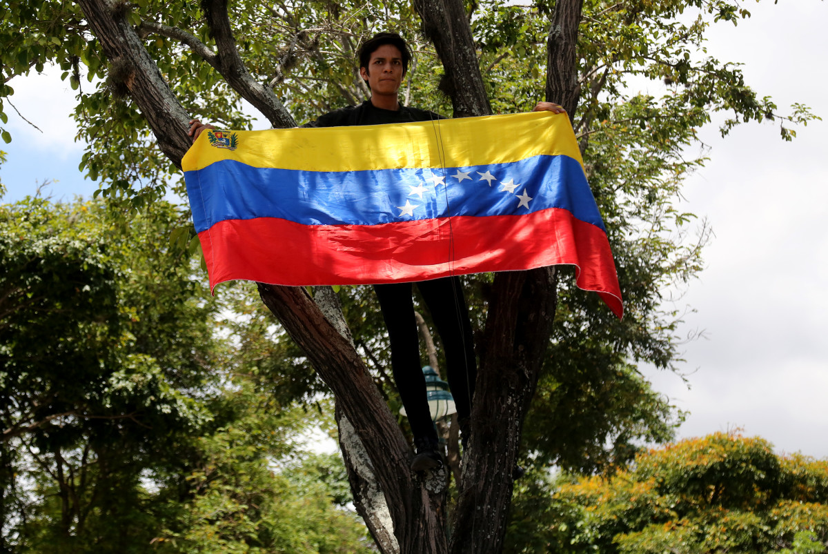 A student standing in a tree displays a Venezuelan flag during a rally in support of opposition leader Juan Guaidó and against Nicolás Maduro at Universidad Central de Venezuela on May 2nd, 2019, in Caracas, Venezuela. After two days of violent clashes between pro-Guaidó and pro-Maduro groups including civilian, police, and military forces that resulted in four dead and over 100 wounded, Venezuelans supporting Guaidó are taking to the streets and responding to the call for strikes.