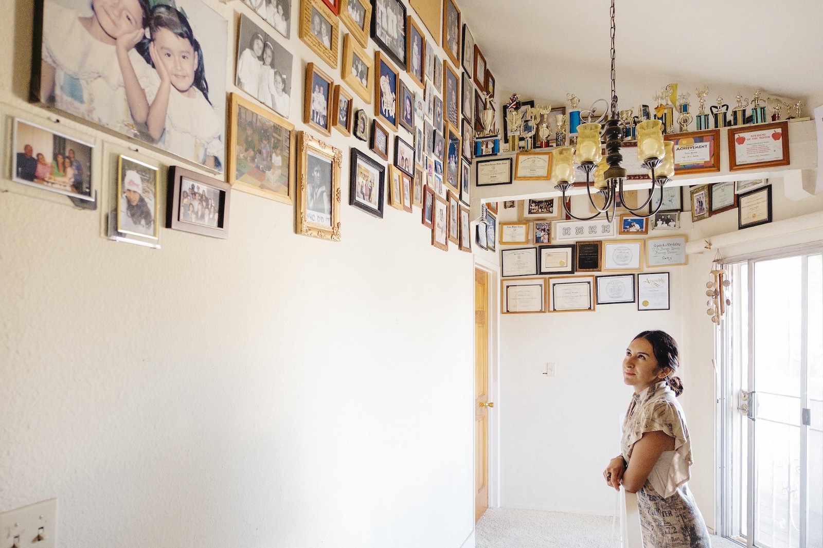 Bernabé mira las fotografías de su familia colocadas en lo alto de las paredes en la casa de Los Ángeles en la que ha vivido desde los diez años.