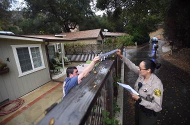 A Los Angeles County sheriff's deputy alerts a resident of mandatory evacuations on January 8th, 2018, in the Creek Fire burn area.