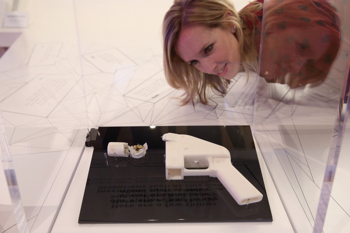 A woman admires a 3-D printed handgun on display in a museum.