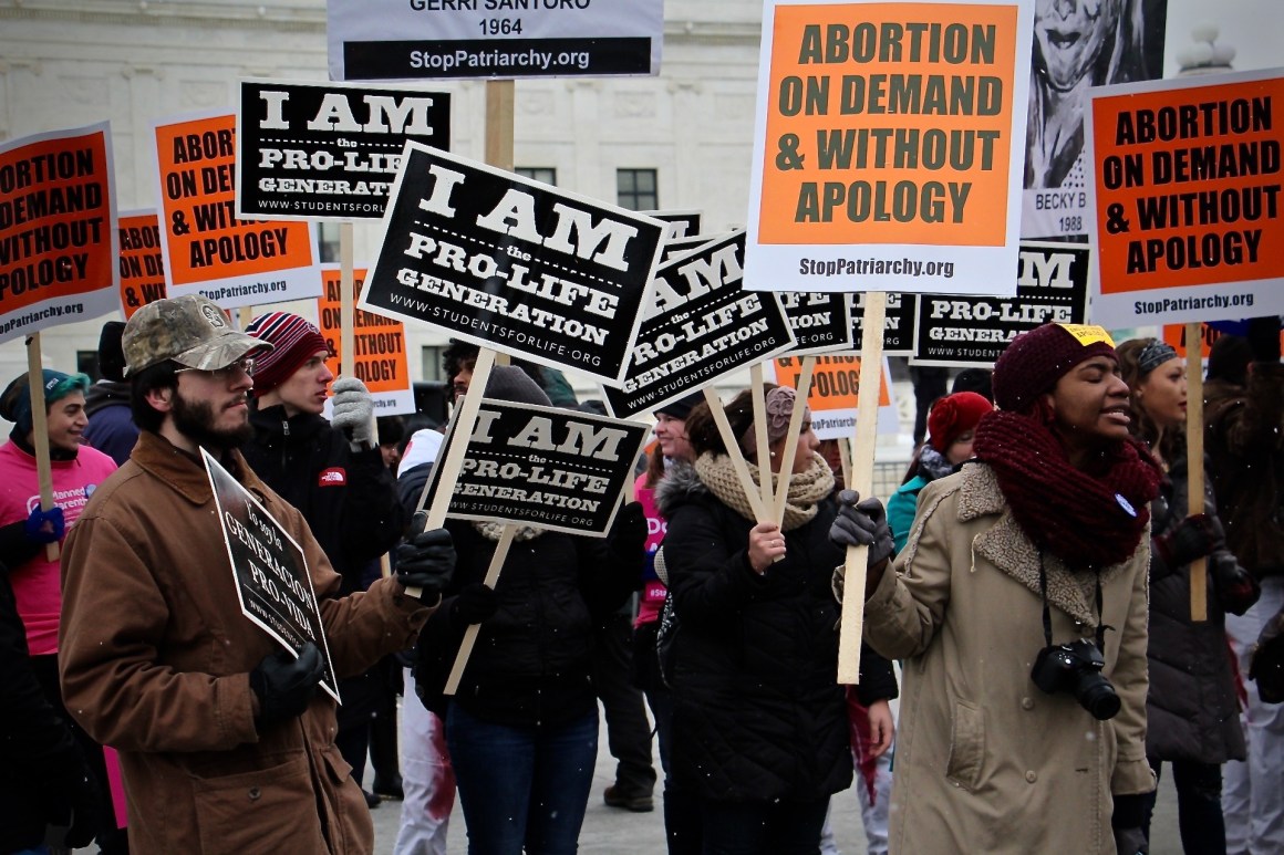 People carry pro-life and pro-choice signs during the 2016 March for Life in Washington, D.C.