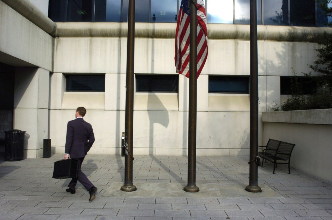 A businessman walks past a U.S. flag flying at half mast as people return to work at the Fulton County Superior Courthouse on March 14th, 2005, in Atlanta, Georgia.