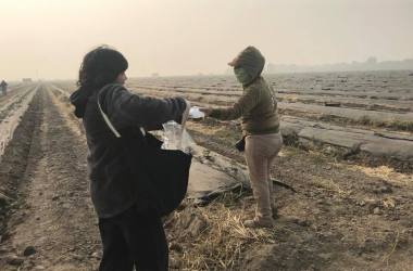 Paulina Cortes, a community activist from San Jose, gives a protective particulate mask to a farmworker in Stockton, California, on November 16th, 2018.