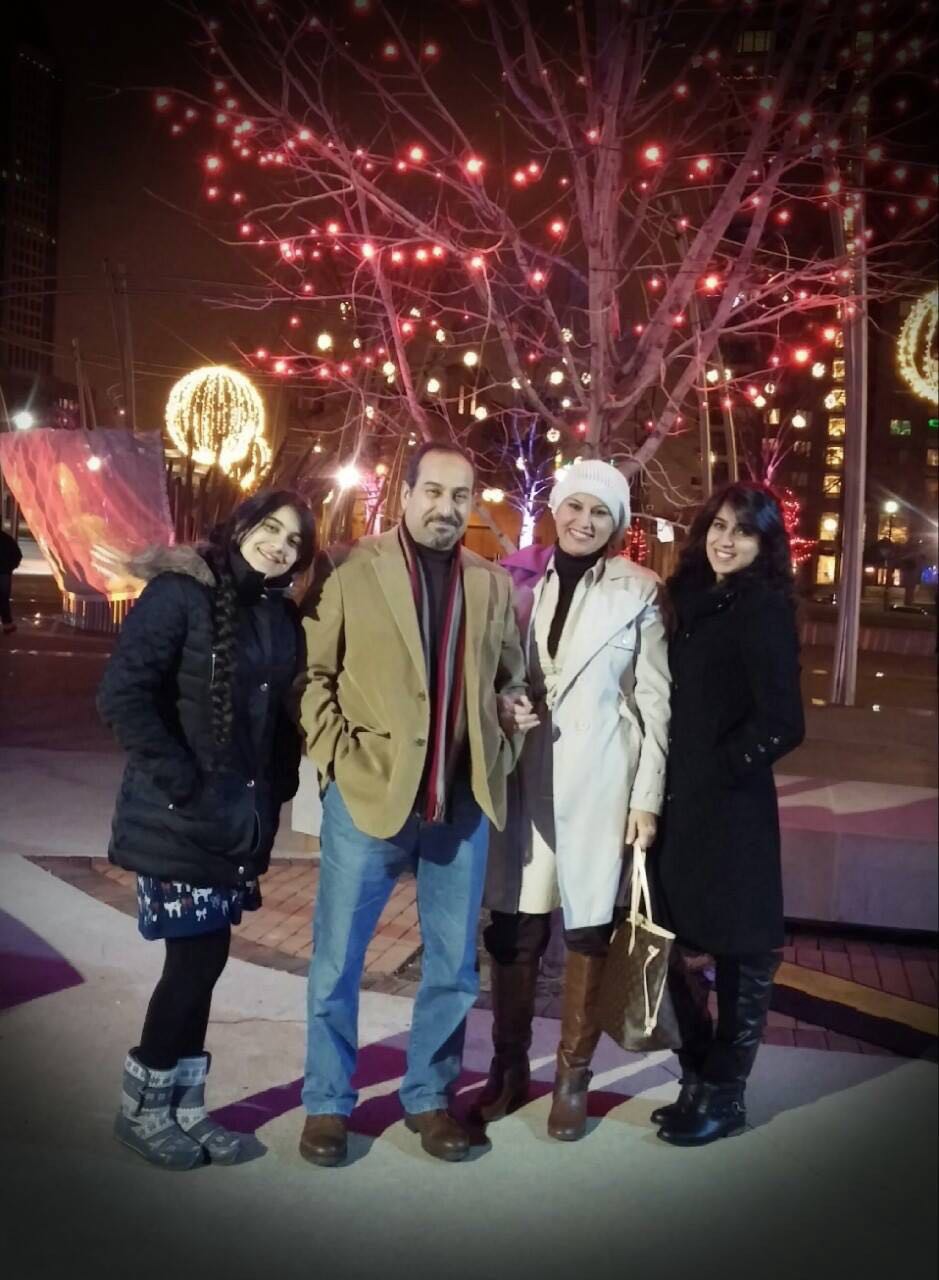 Photo showing a family of four in front of a tree lit for Christmas