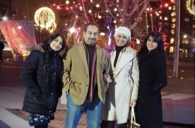 Photo showing a family of four in front of a tree lit for Christmas