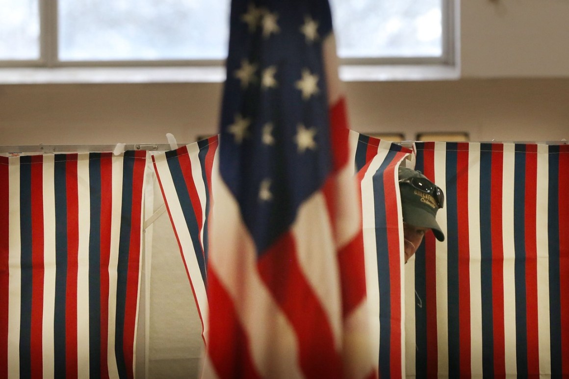 A man exits a voting booth inside of a middle school serving as a voting station.