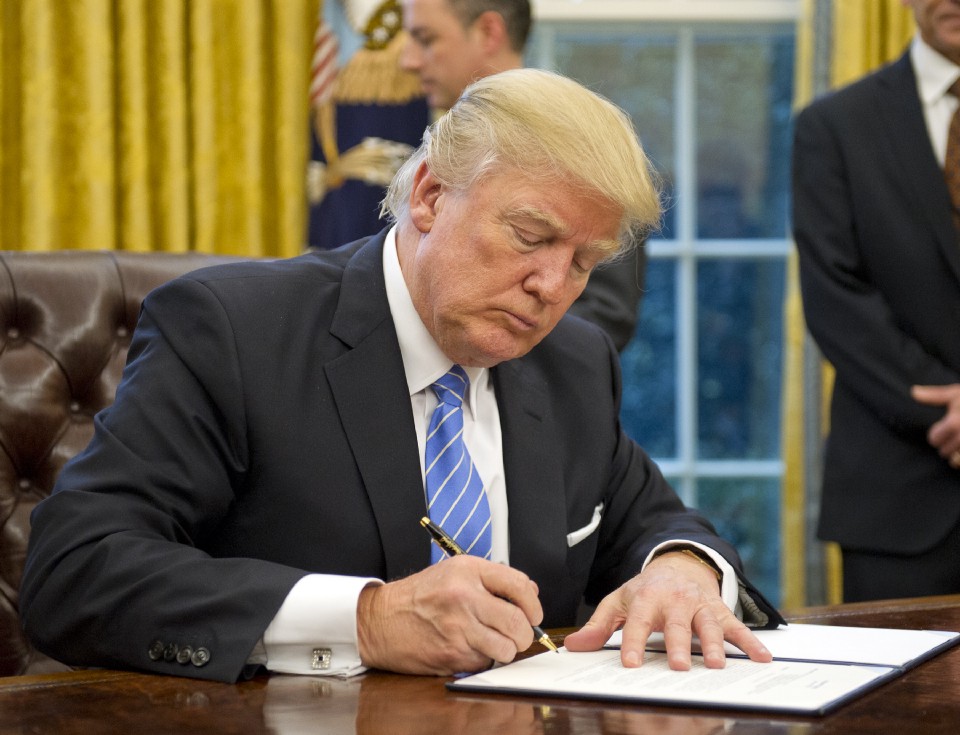 Photo showing President Donald Trump signing executive orders at his desk