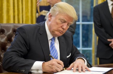 Photo showing President Donald Trump signing executive orders at his desk