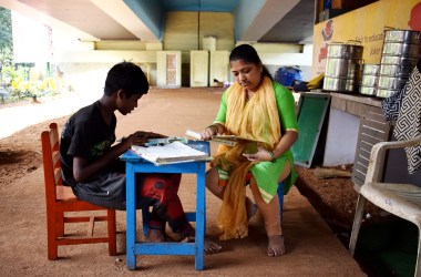 A teacher sits with Vishal Pawar at Signal School.