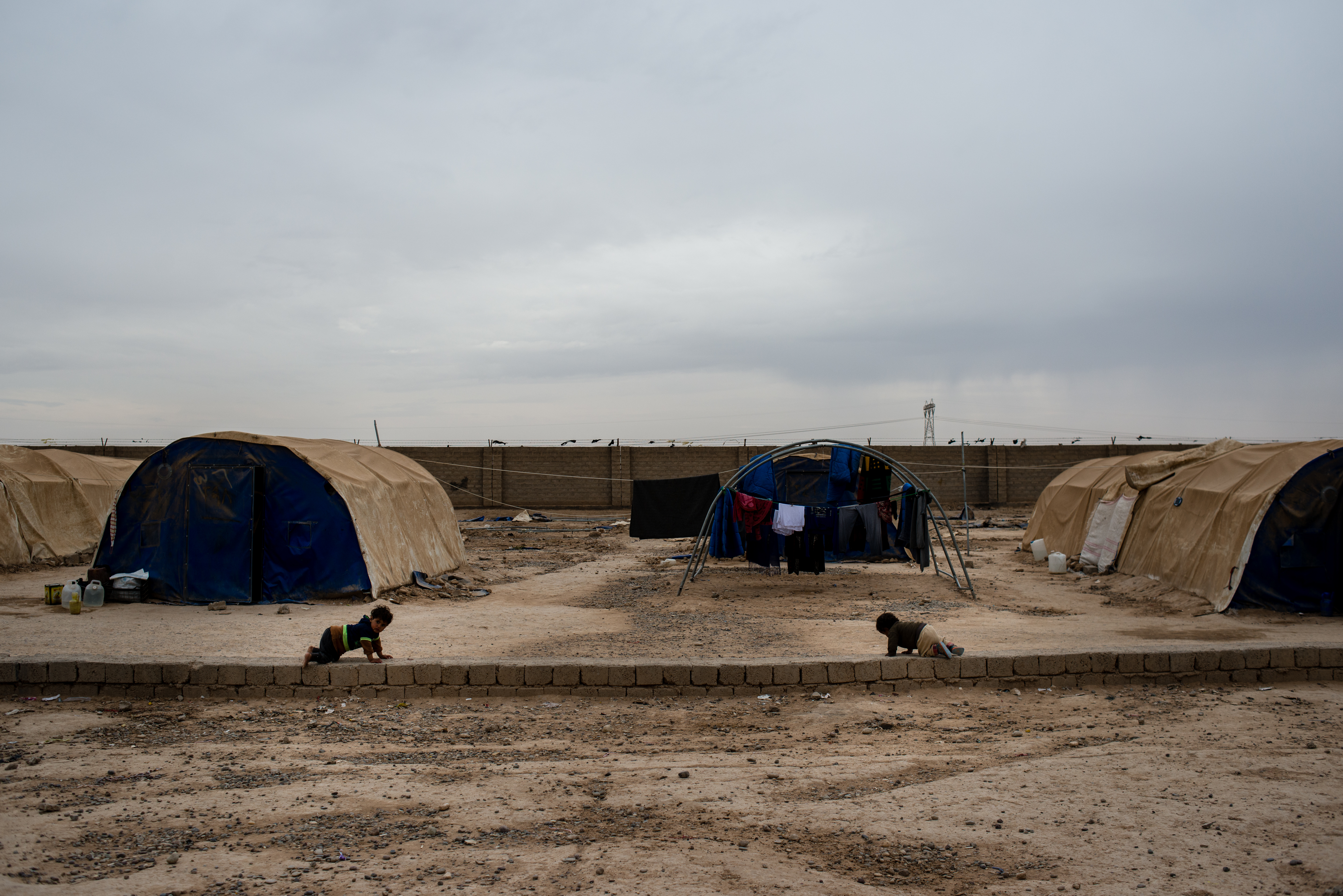 Babies crawl along cinder blocks in Shahama camp outside Kirkuk. The camp holds families with suspected ties to ISIS.