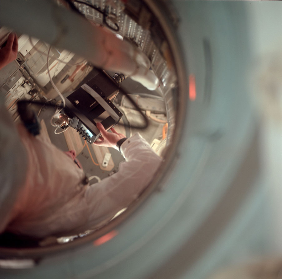 Mike Collins took this photo of Neil Armstrong floating in the tunnel connecting the Lunar Module and the Command Module. Armstrong is using a TV to document Buzz Aldrin conducting an inspection.