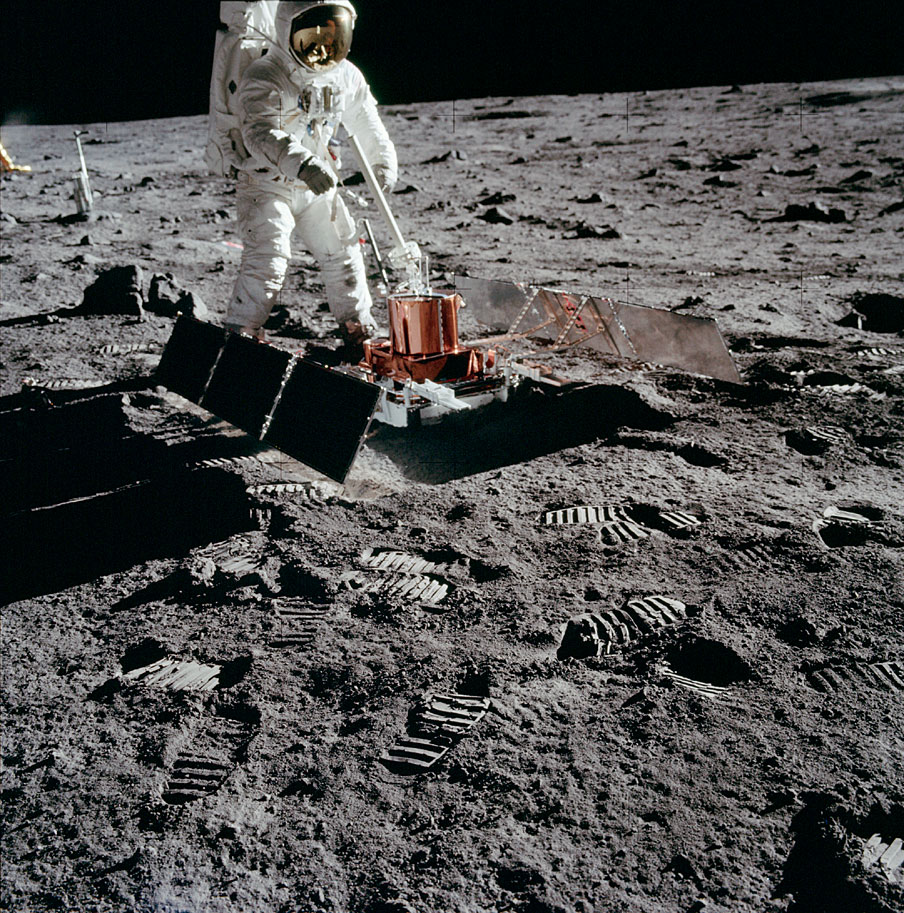 Buzz Aldrin locates a deployment site for the laser reflector and passive seismometer, then sets them up 14 and 19 meters, respectively, south of the Lunar Module.