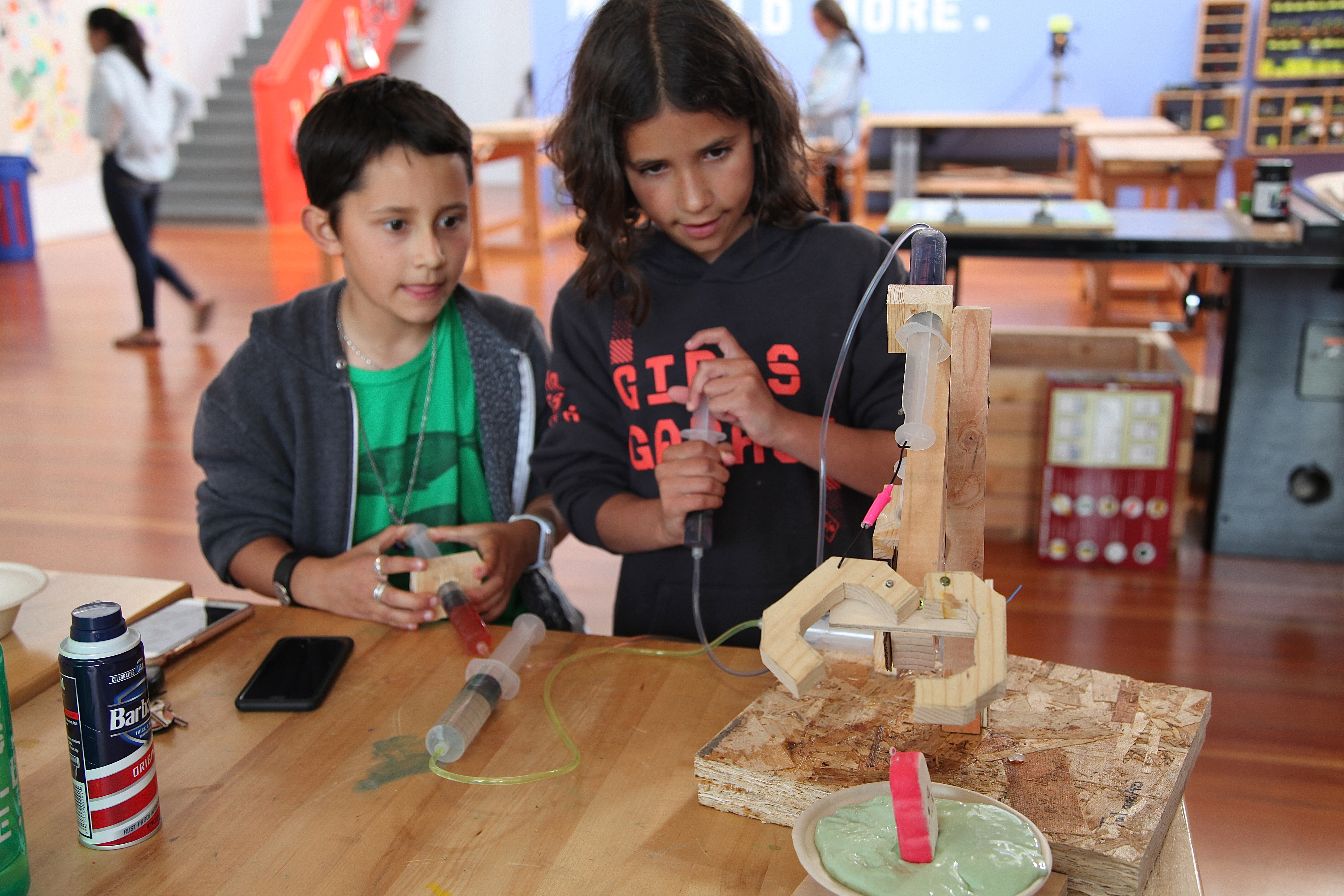 Azi, nine, (left) and Tal, 11, attempt to pull a squishy toy from a bowl of slime using the mechanical claw they constructed at a workshop at Girls Garage, in Berkeley, California.