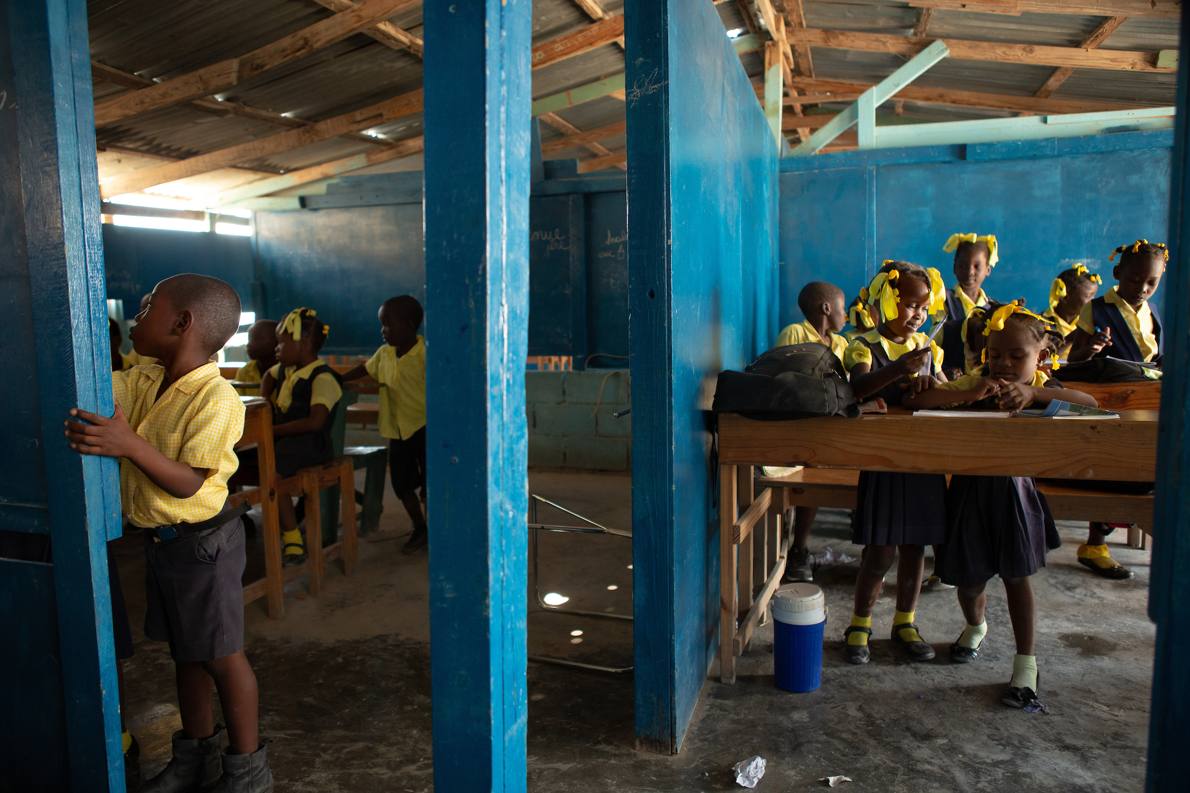 Students of various grades participate in classroom lessons in classrooms separated by partial walls at Institution Mixte Cean Carmen, a K-12 school in the Village de Pecheur neighborhood of greater Canaan.