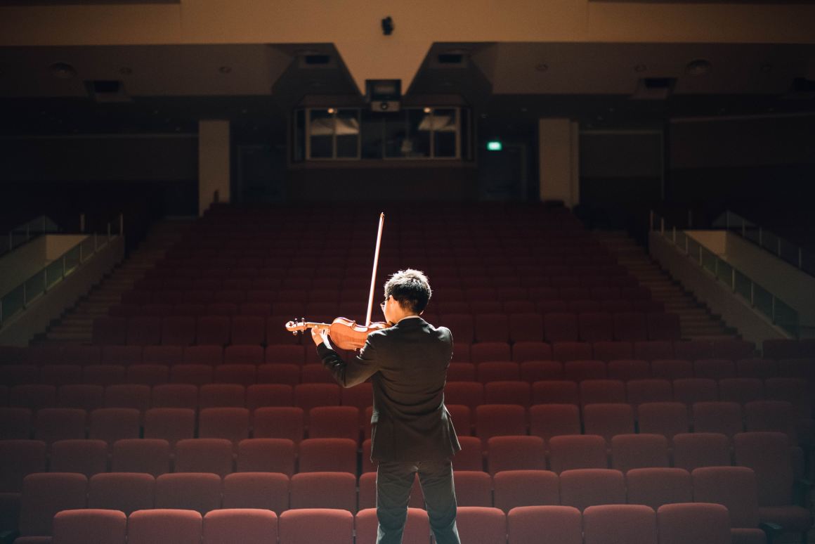 A man plays the violin in a theater.