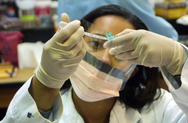 Photo showing a scientist pipetting a liquid into a storage tube