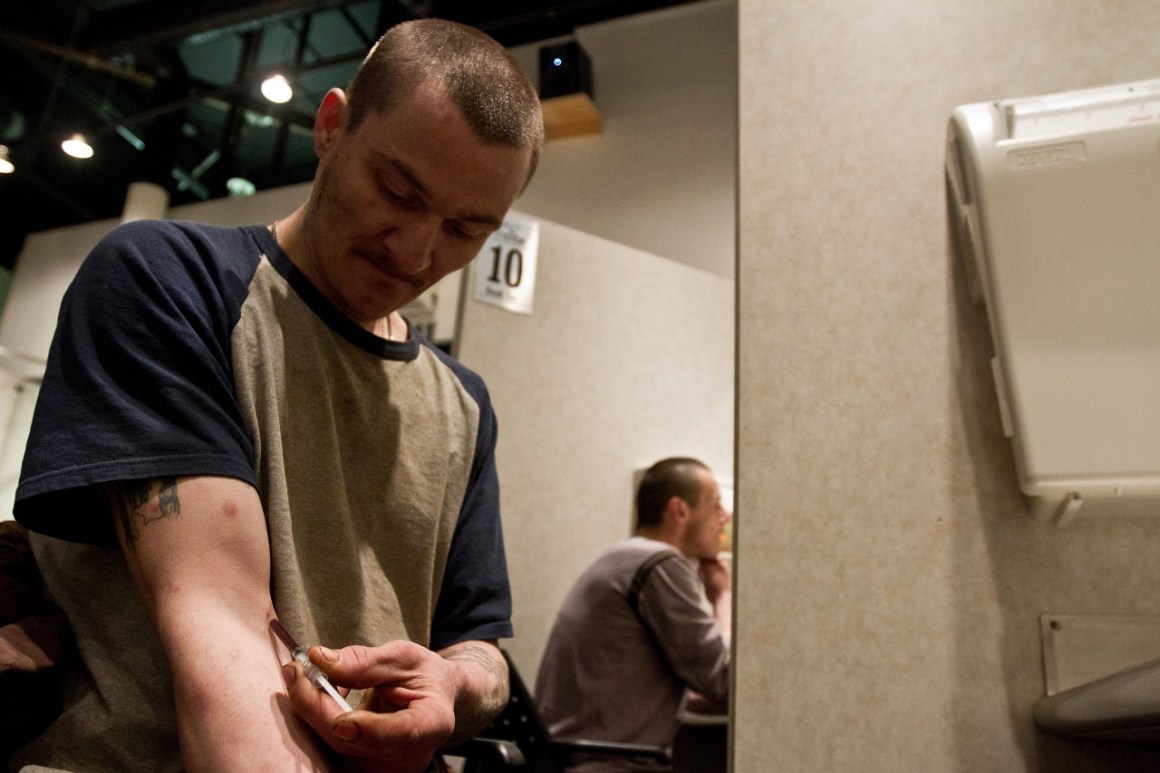 Photo showing a man injecting himself with a substance in a supervised injection booth in Vancouver, B.C.