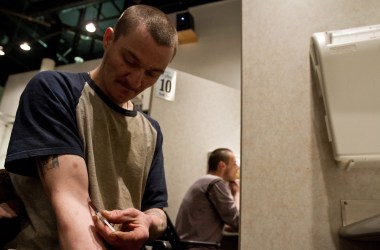 Photo showing a man injecting himself with a substance in a supervised injection booth in Vancouver, B.C.